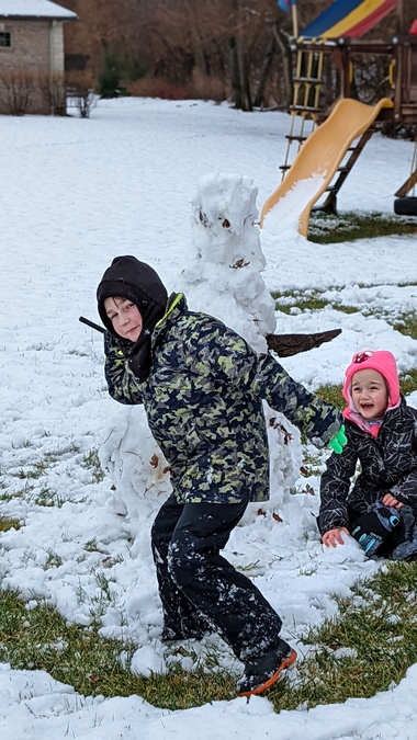 snow day 2021 Wyatt winding up to throw a big snowball at me while Ayla prepares her snowball in the background.
