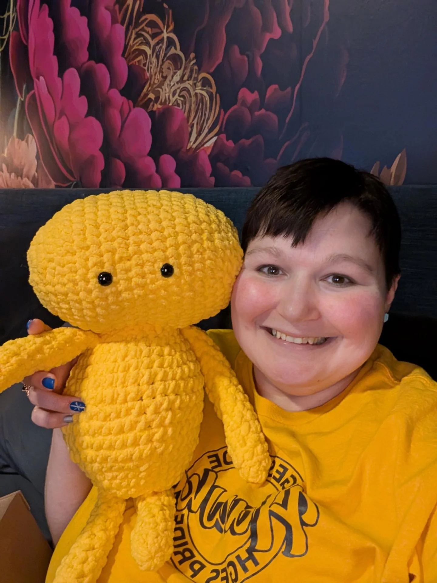 Person holding a yellow crocheted character