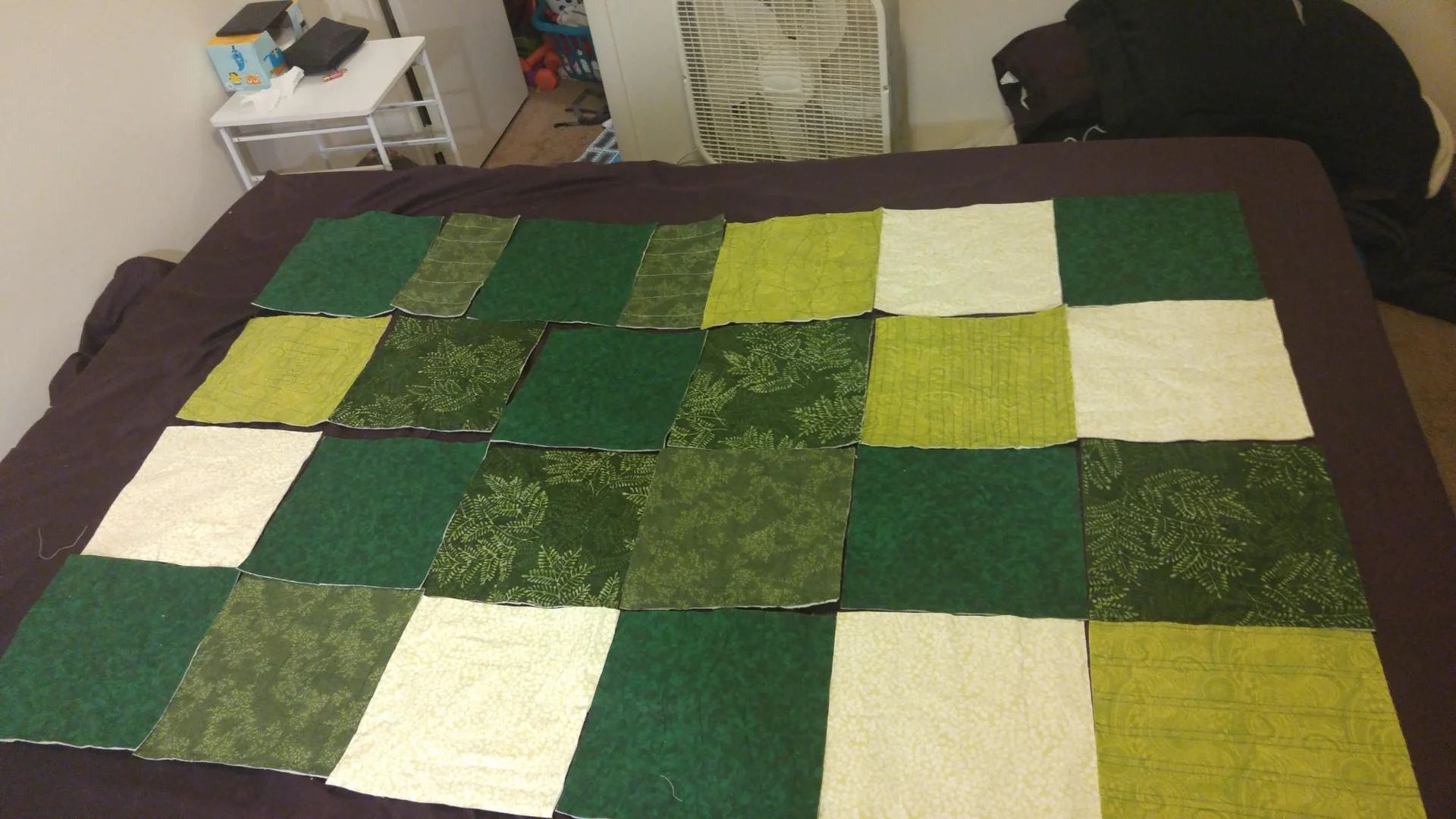 Green patchwork quilt laid out on a bed