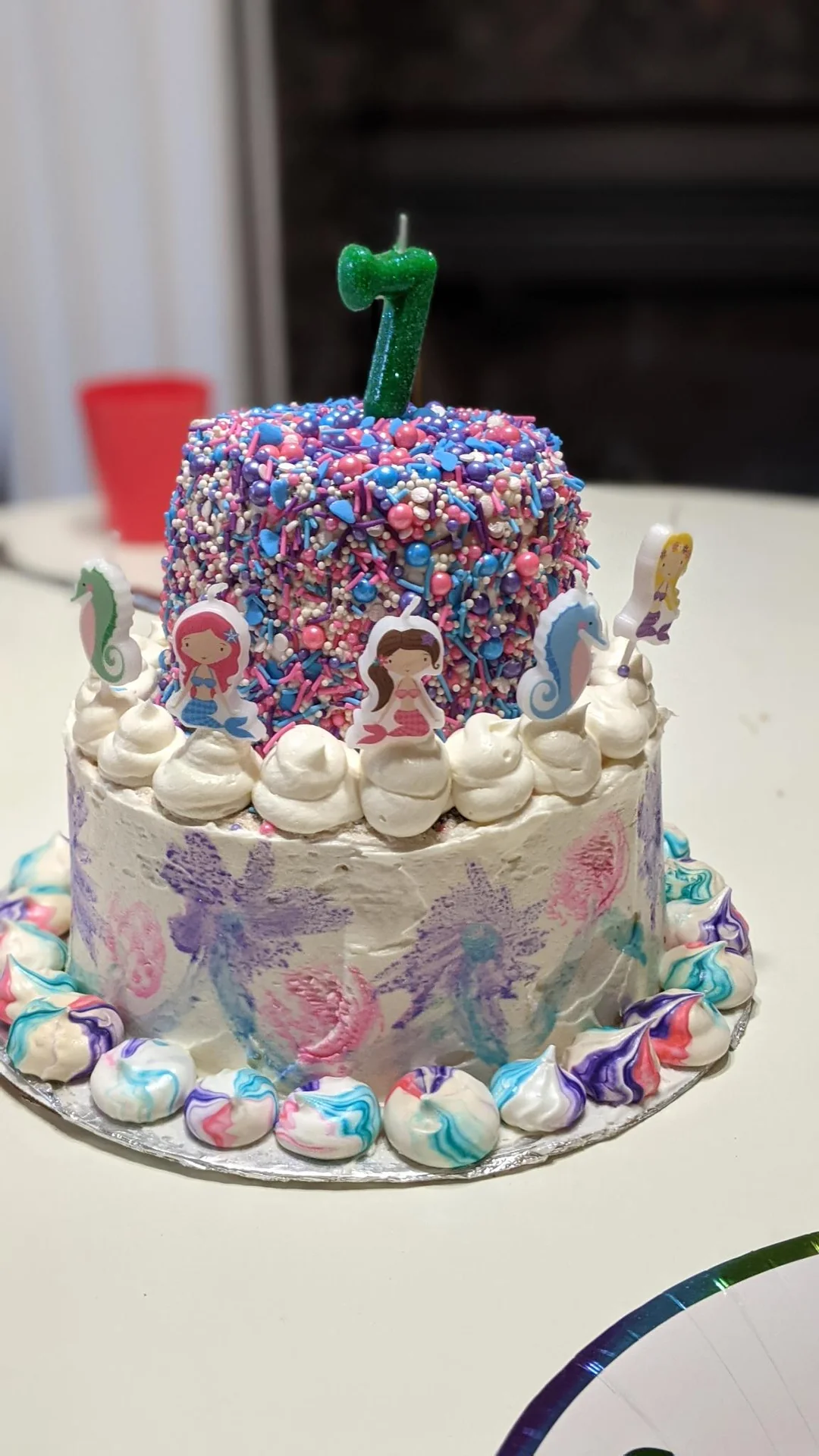 Tall white birthday cake with colorful frosting and sprinkles