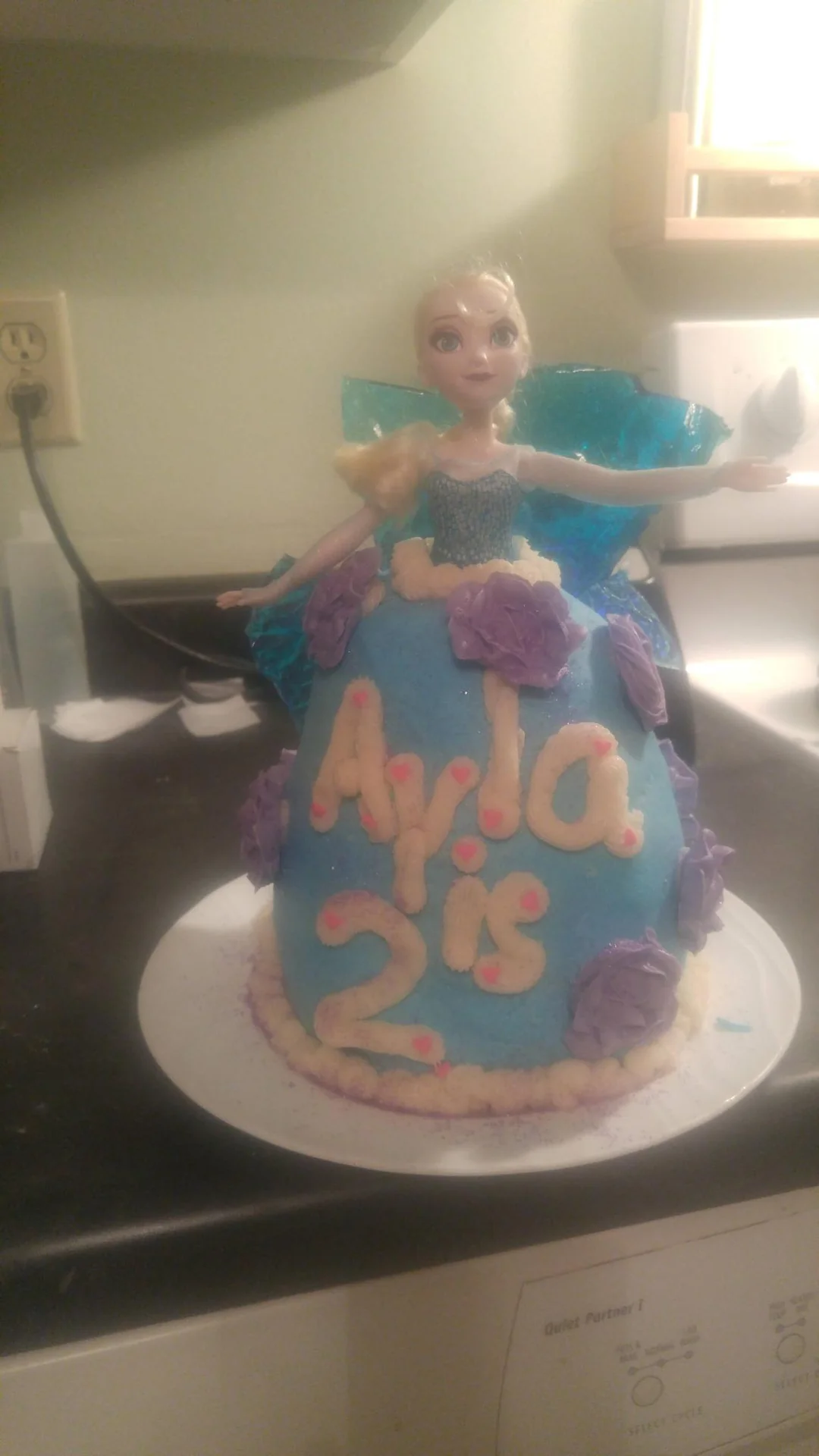 Child standing behind a tall decorated birthday cake