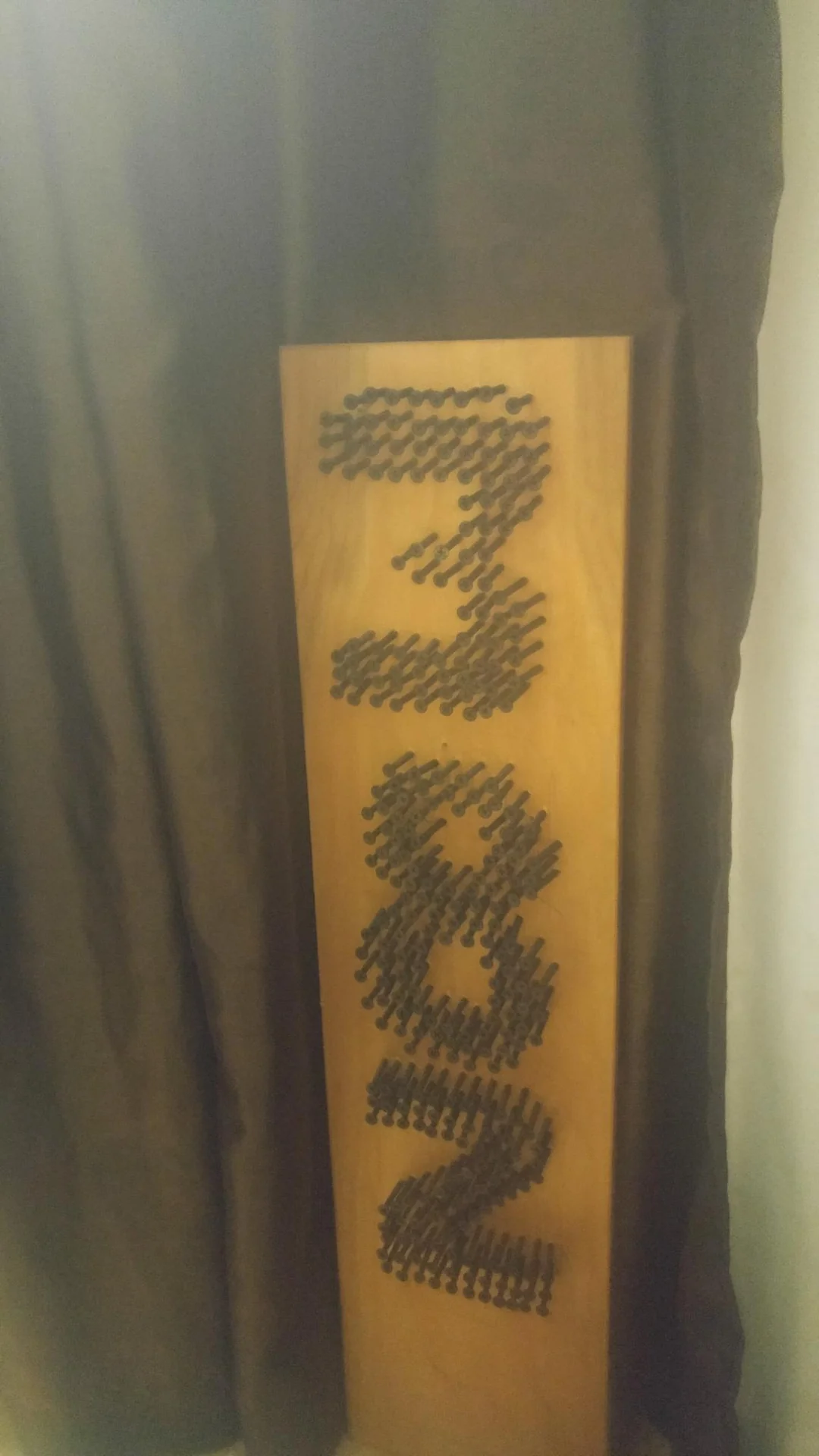 Narrow wooden sign with dark vertical lettering