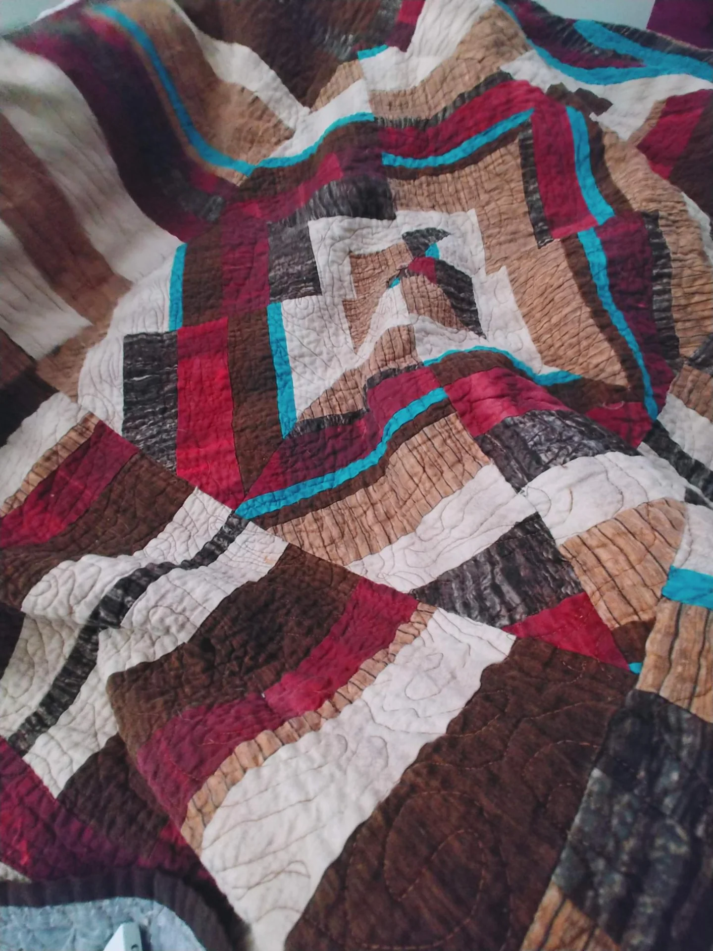 Patchwork quilt with burgundy, cream, and blue strips