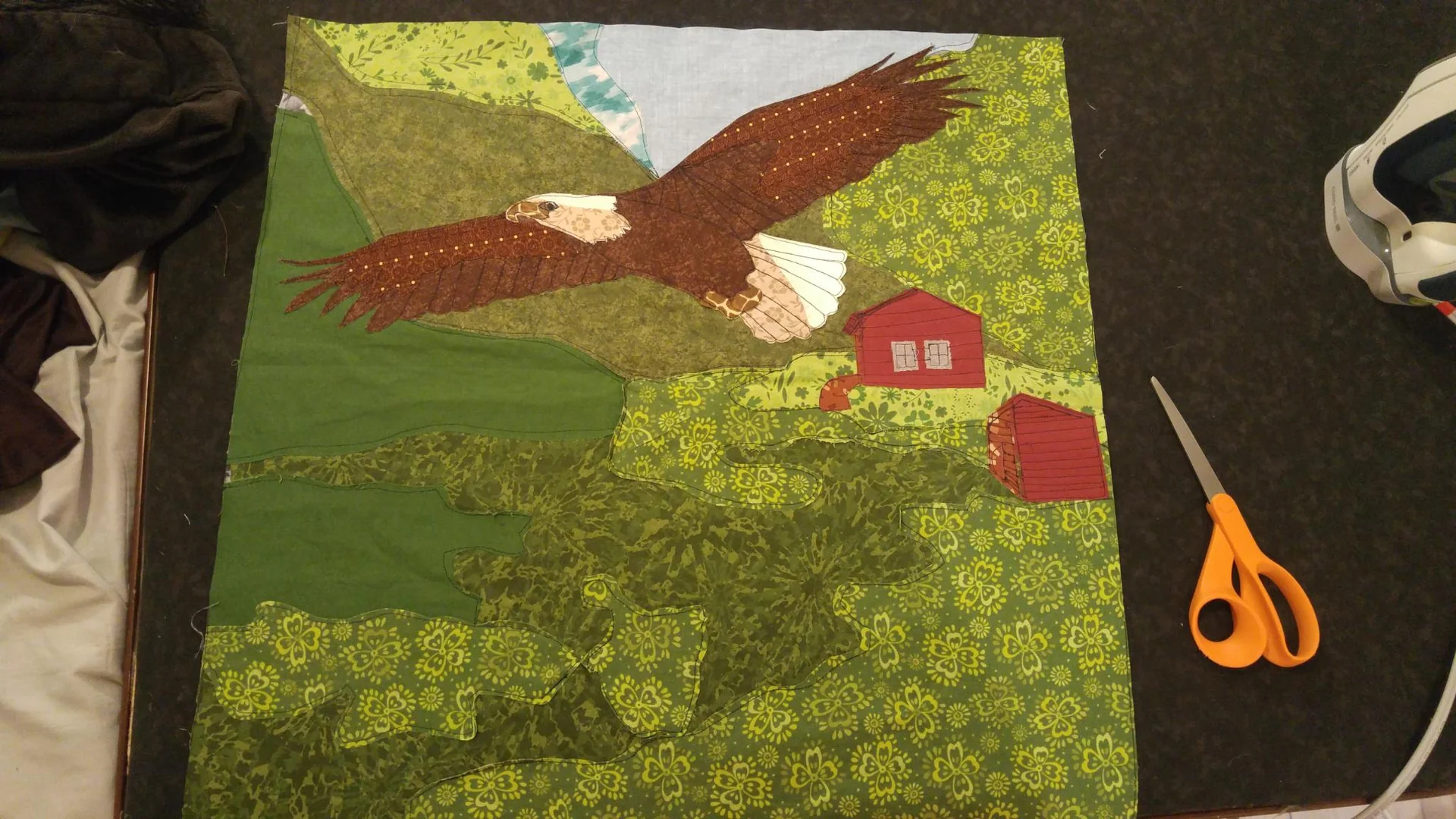 Eagle appliqué quilt laid out beside sewing scissors