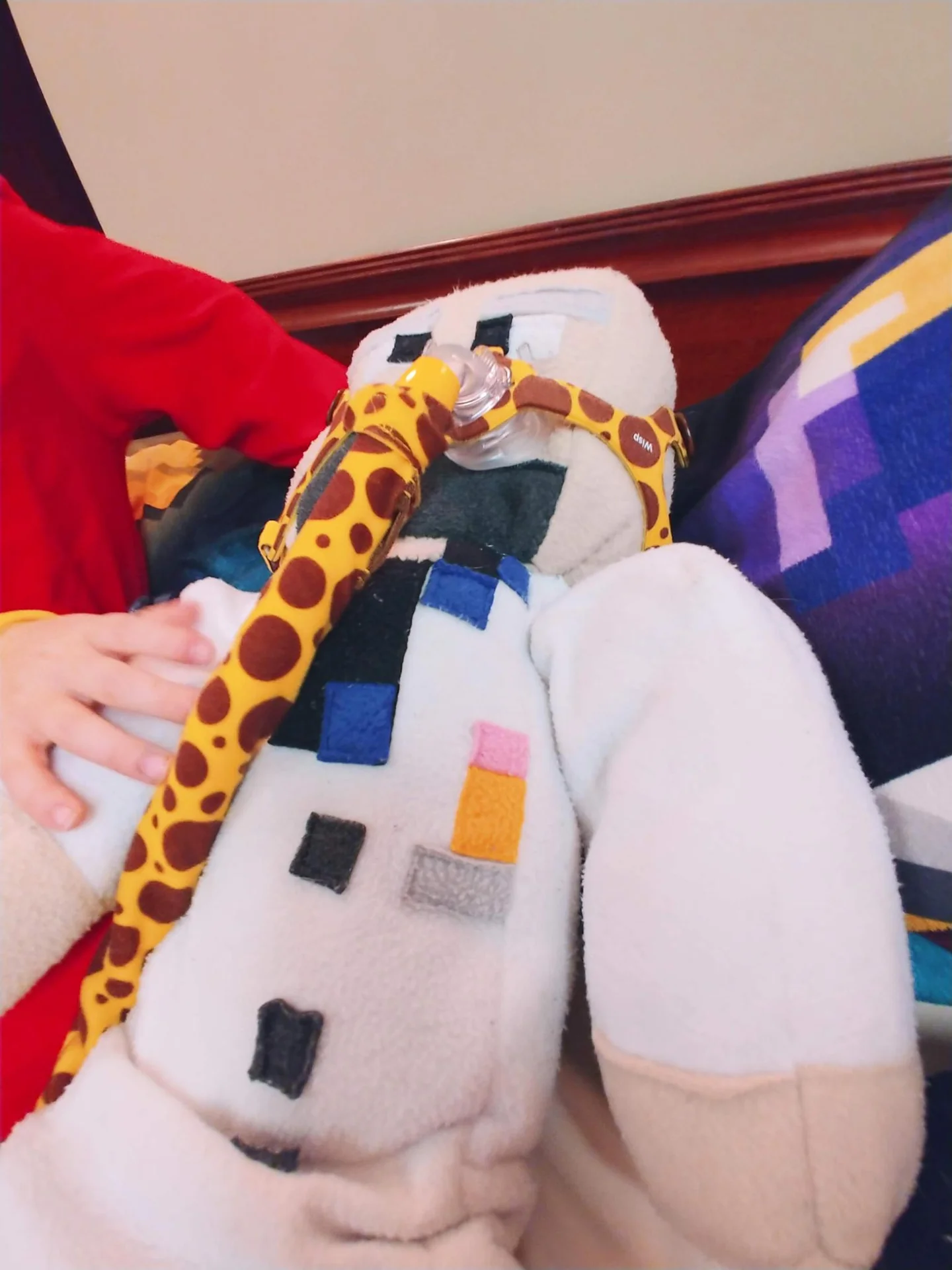 White handmade plush figure lying beside a toy giraffe