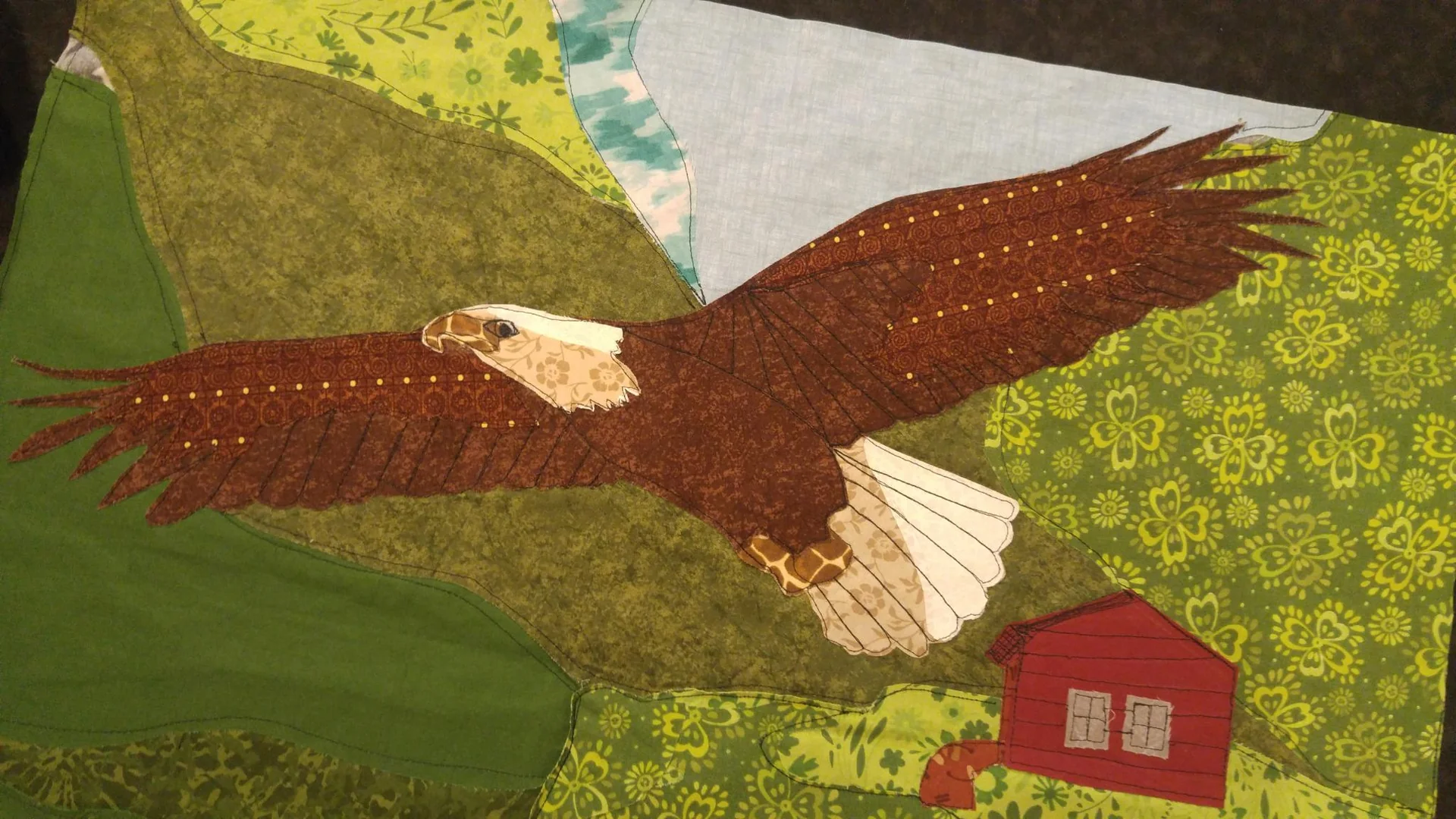 Close view of an eagle appliqué on a landscape quilt