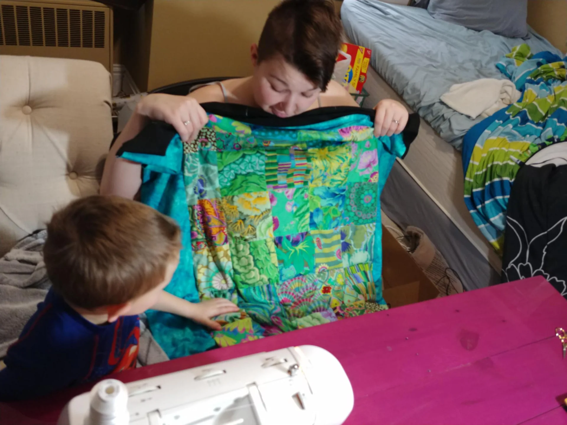 Adult and child holding up a colorful quilt