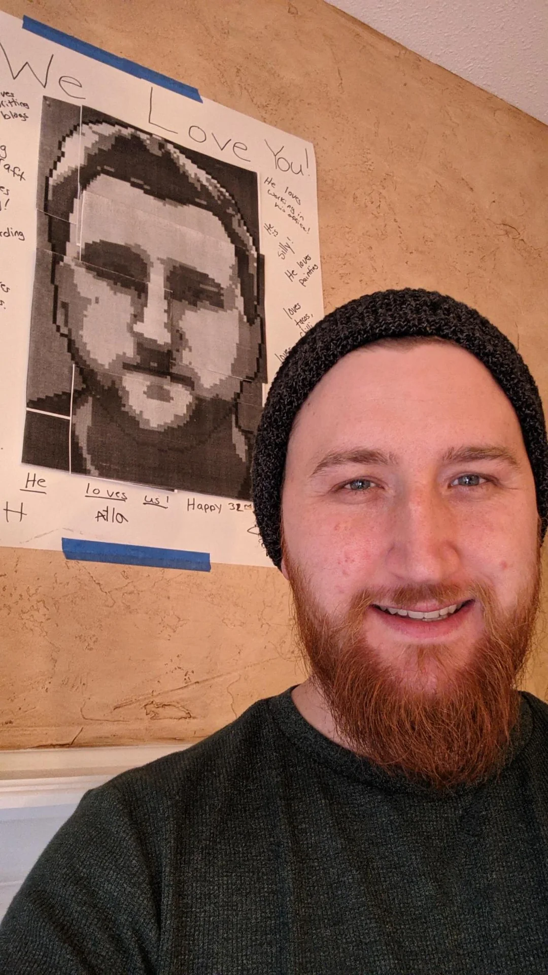 Man smiling beside a large portrait poster
