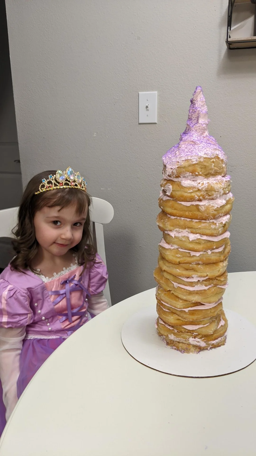 Child standing beside a tall unicorn birthday cake