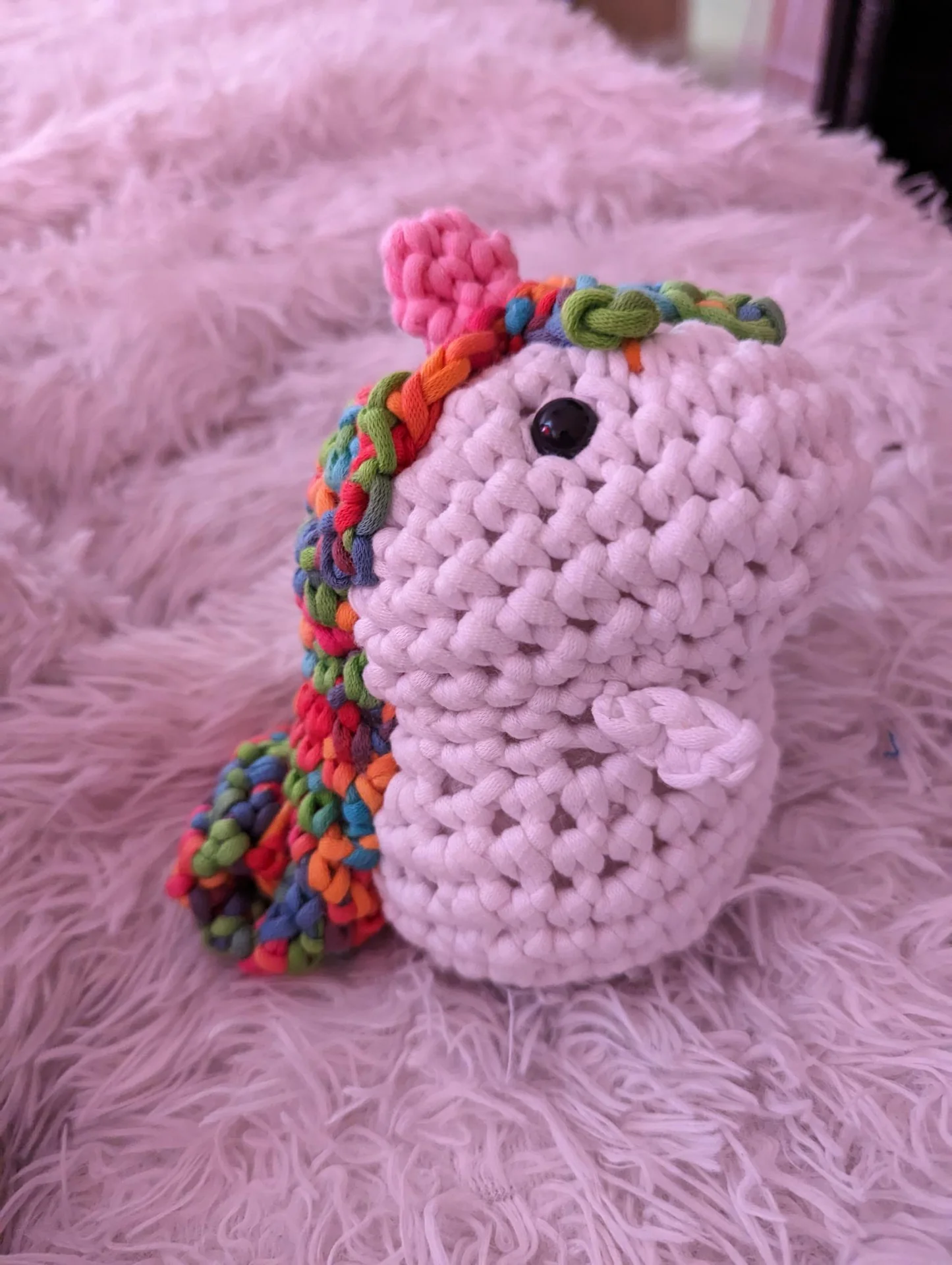 Pink crocheted figure on a fluffy blanket