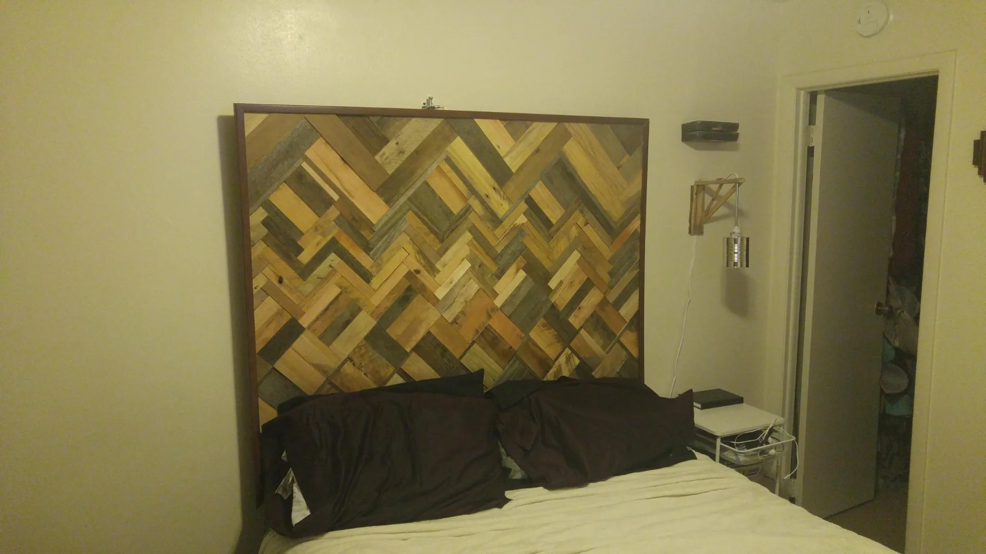 Geometric wood wall hanging above a bed
