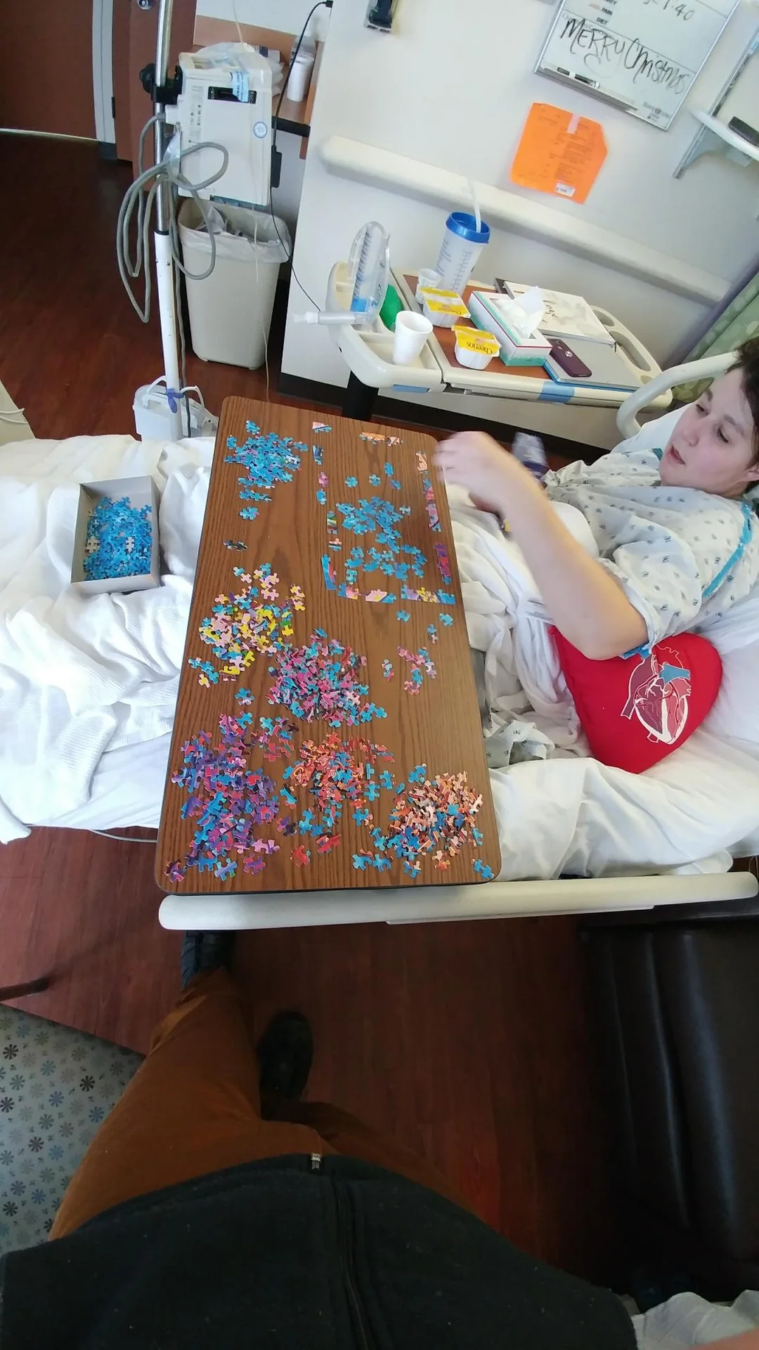 Person assembling a colorful jigsaw puzzle in bed