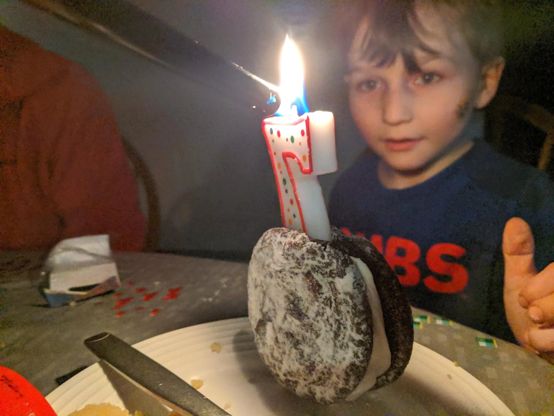 Child leaning toward a lit candle on a small cake