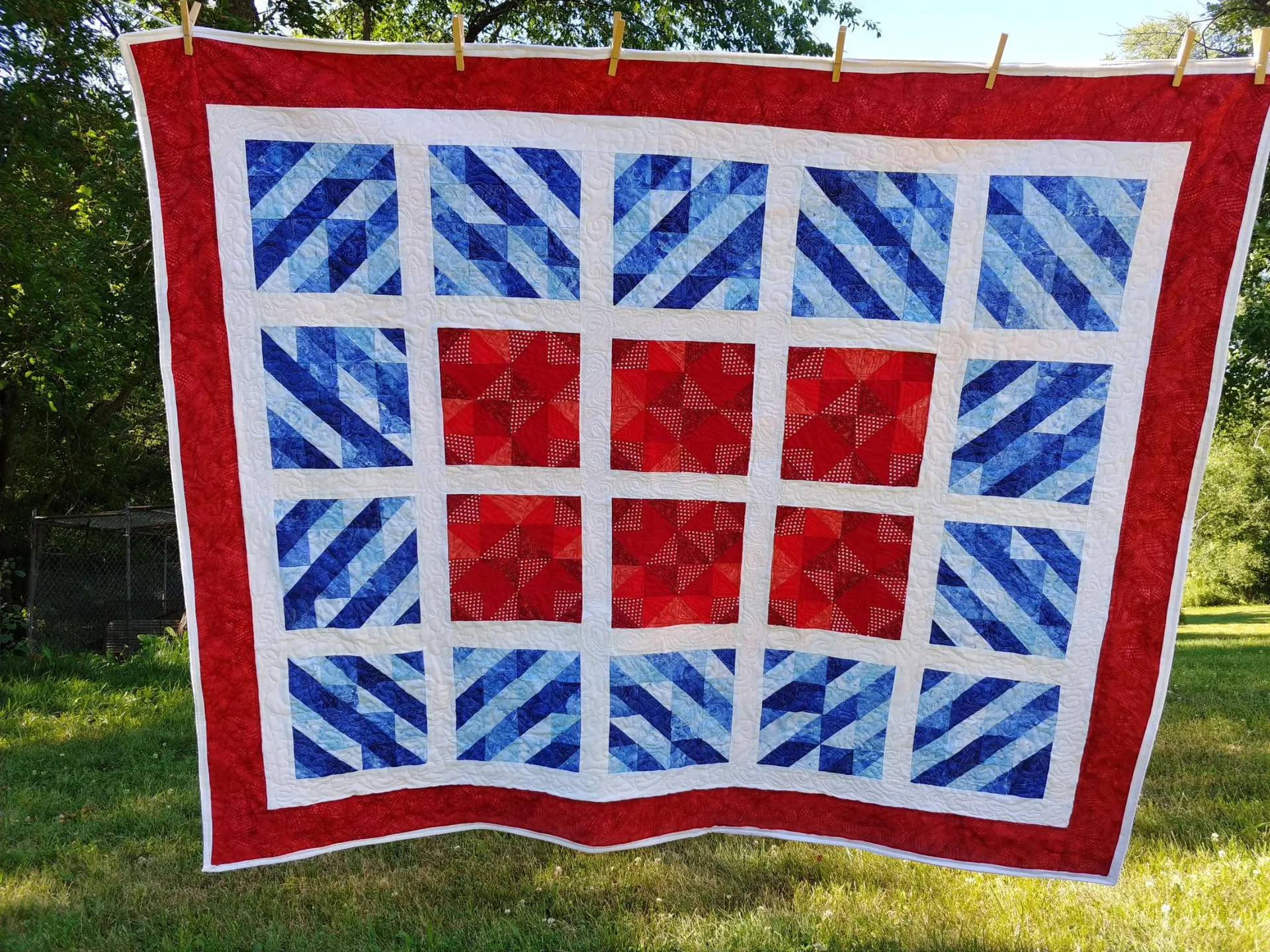 Red, white, and blue quilt hanging outdoors