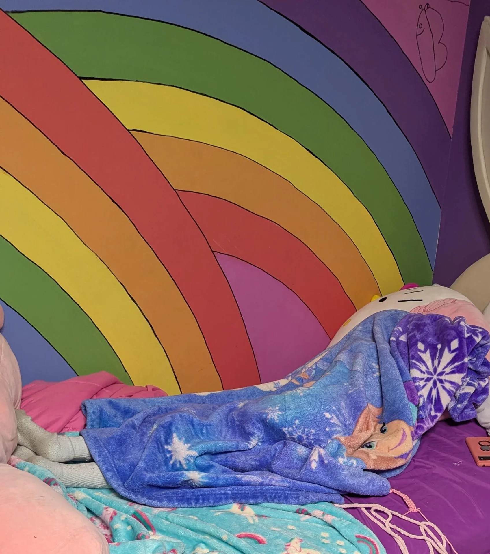 Rainbow mural behind a child’s bed