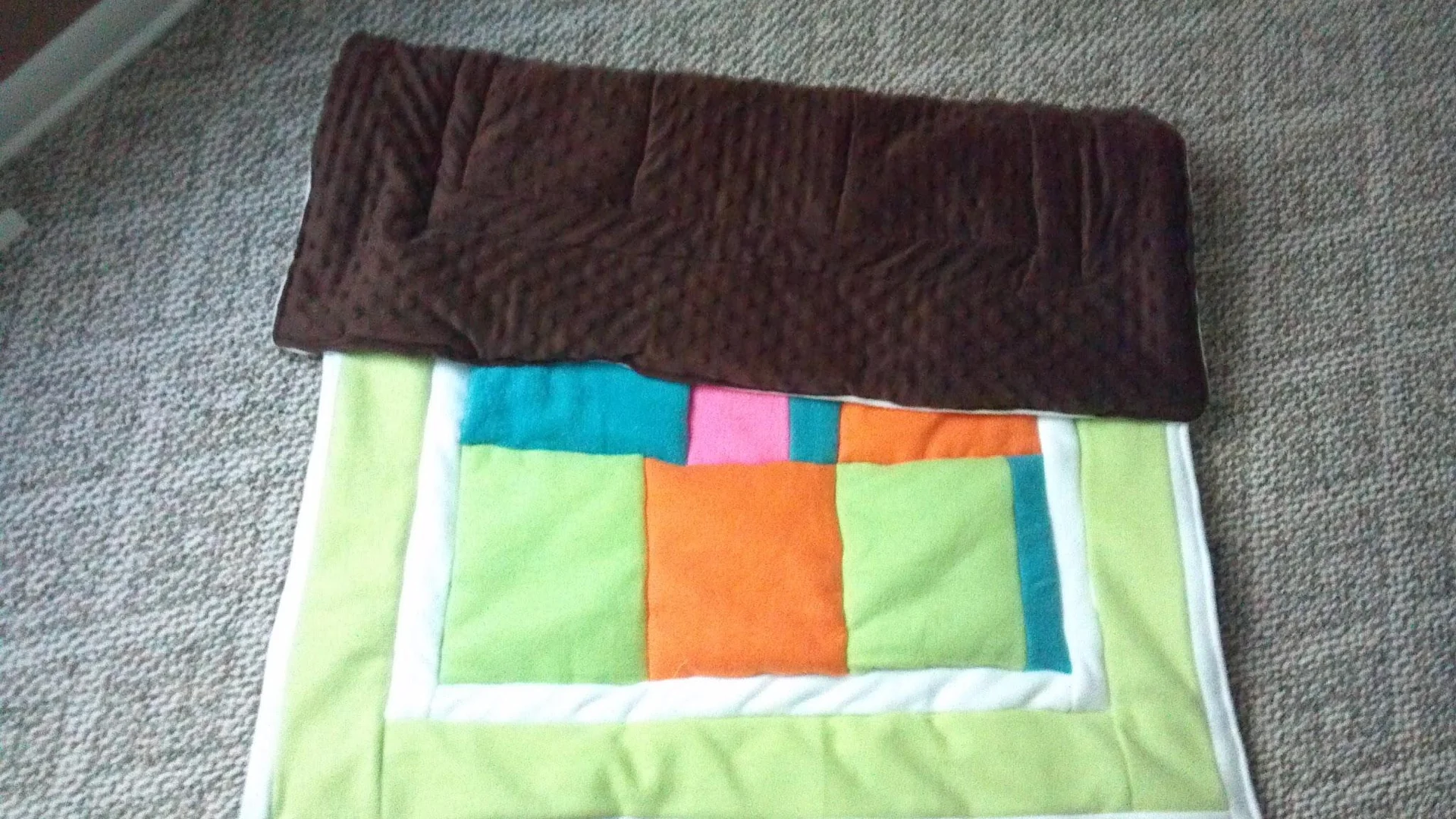 Partly folded quilt with bright blocks beneath a dark border