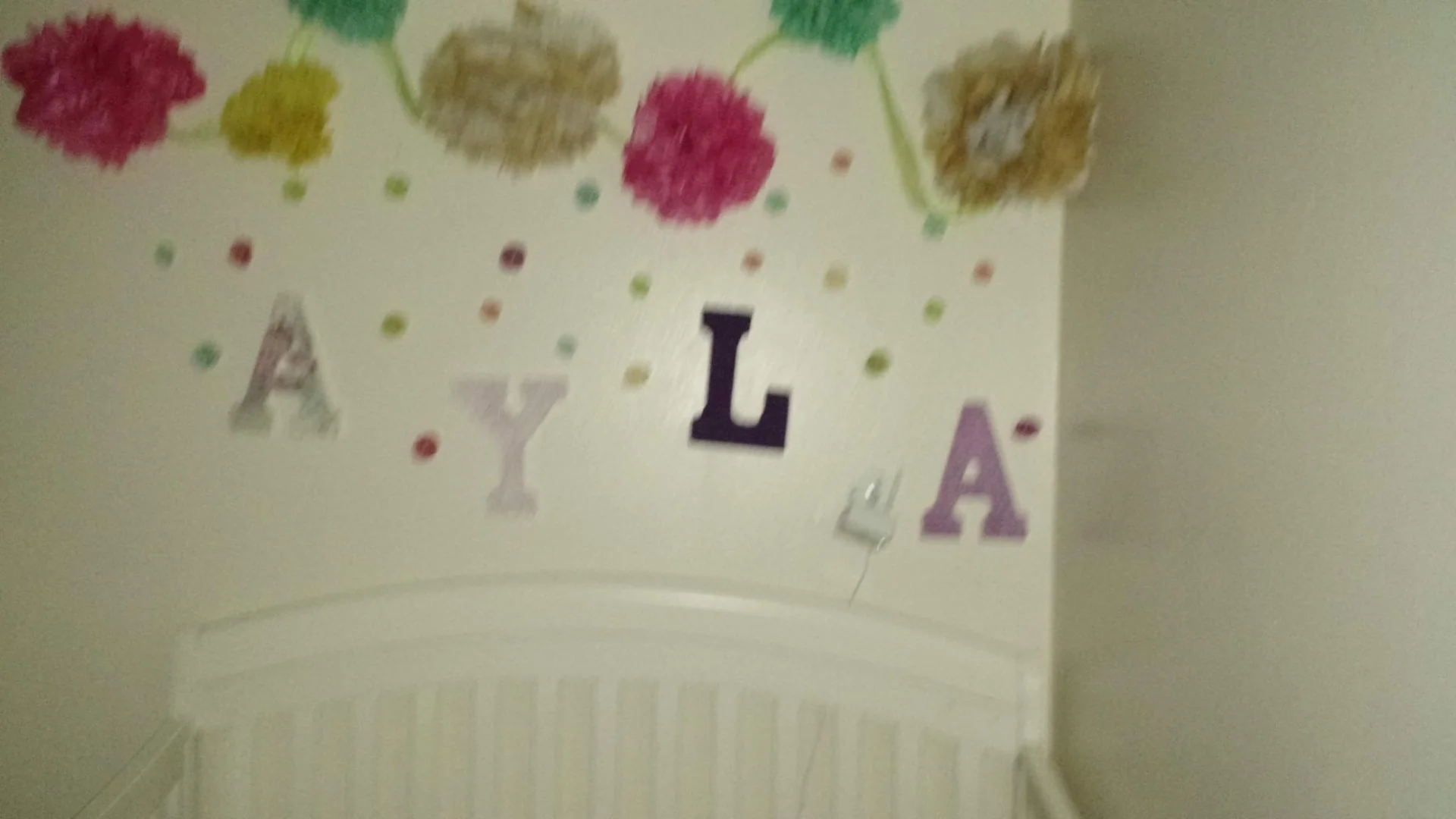 Letters spelling AYLA above a white bed