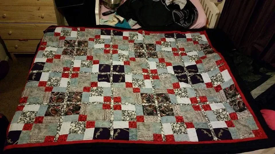 Red, gray, black, and white patchwork quilt on a bed